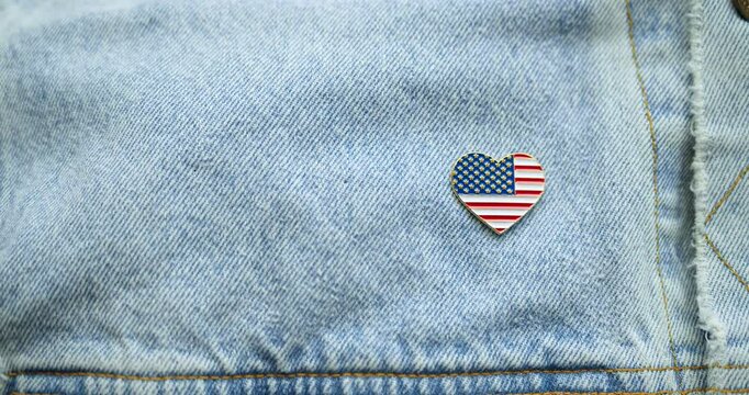 American blue collar worker pinning shiny lapel pin in the shape of a heart with the US American flag. Celebrating patriotism, Labor Day, manufacturing in America, or another patriotic USA holiday.