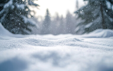 Fototapeta premium Snowy landscape with soft snowdrifts and gentle falling snow, set against a blurred background of winter trees and a cloudy sky