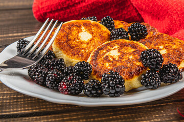 Cottage cheese pancakes with fresh blackberries on a white flat white plate
