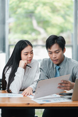 Two business professionals reviewing documents together in a bright, modern office environment.