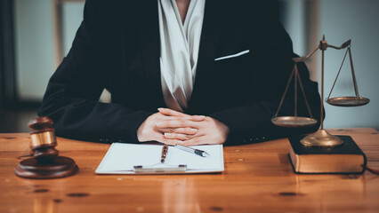 A professional lawyer in a suit sits at a desk with legal documents and scales of justice, symbolizing law and justice.