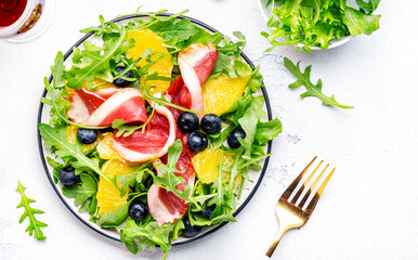 Tasty salad with grilled duck and juicy orange, blueberry and arugula on white background, top view