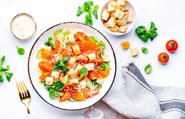 Delicious salad with salmon, iceberg lettuce, croutons, grated parmesan cheese and caesar dressing. White background, top view