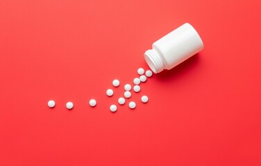White Pill Bottle with Small Round Pills Spilling Out on a Red Background
