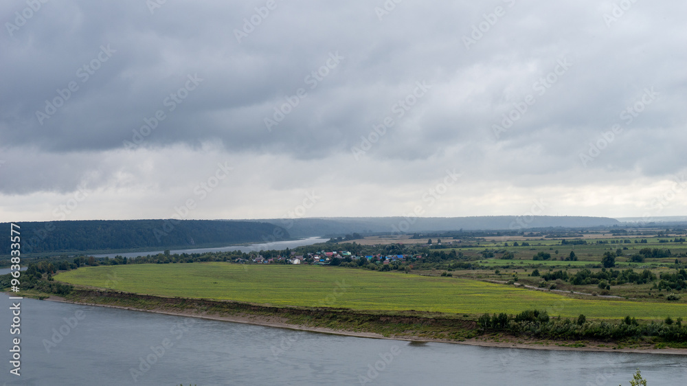 Poster A cloudy day with a river and a field in the background