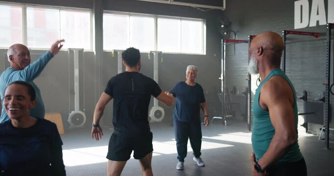 Coach, high five and fitness in group at gym for training, people or celebration for goal at club in retirement. Person, elderly men and women for diversity with success, exercise or cheers in class
