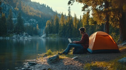 A peaceful camping scene by a lake, featuring a person working on a laptop beside a tent in a serene forest setting.