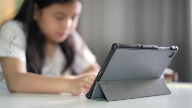 closeup computer tablet with blur asian child or kid girl reading on notebook or study online class and learn from home by pad or young people studying learning by back to school technology education