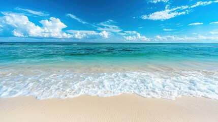 Obraz premium A pristine white sandy beach with crystal-clear turquoise water and a few gentle waves under a bright blue sky.