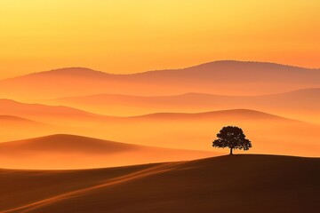 Obraz premium A tranquil scene unfolds with mist-covered hills at dawn, featuring a solitary tree silhouetted against a fiery orange horizon.
