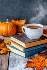 A cozy autumn scene featuring a steaming cup of tea atop a stack of books with vibrant fall leaves and a small pumpkin.