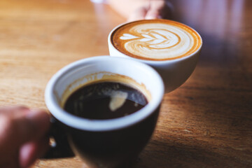 Closeup image of couple people clinking coffee mugs in cafe