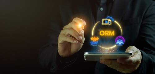 ORM, Online reputation management concept, monitoring and improving how your business is viewed online. Businessman shows glowing neon line of ORM icon on virtual screen.