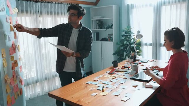 Top view of smart designer holding color palette while project manager looking at design and choosing color for program. Professional businesswoman taking a note while design creative logo. Symposium.