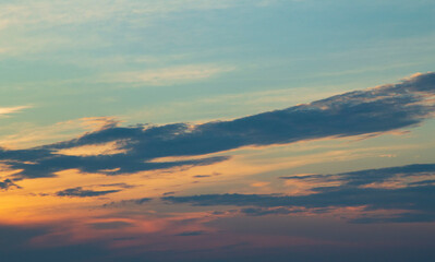 Cumulonimbus mother cloud dissipating into stratocumulus cumulonimbogenitus and Altocumulus clouds at dusk colored by the sun in different shades from yellow to orange