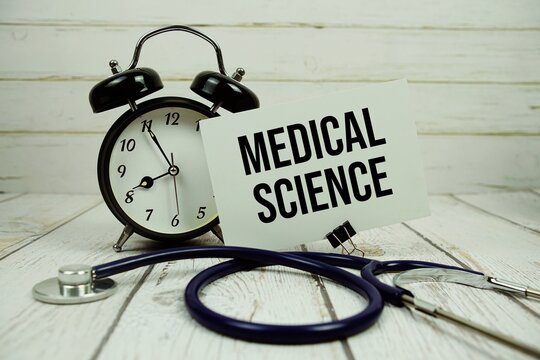 Medical Science text on paper card with alarm clock and stethoscope on wooden background