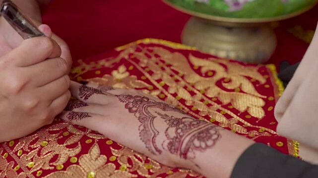 The process of painting henna on the bride's hands. There are many different names for henna tattoo across the globe, such as mehndi, inai, hina, camphire, and hena