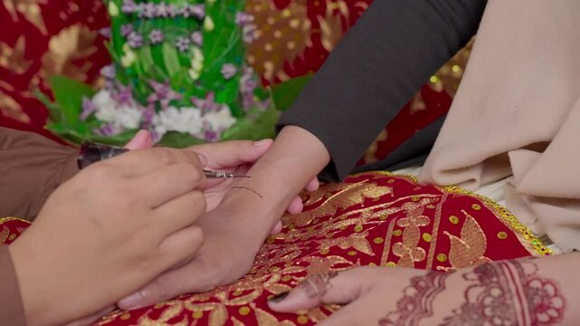 The process of painting henna on the bride's hands. There are many different names for henna tattoo across the globe, such as mehndi, inai, hina, camphire, and hena