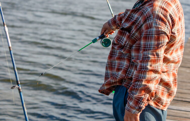 A boy is fishing with a small fishing rod on a pond