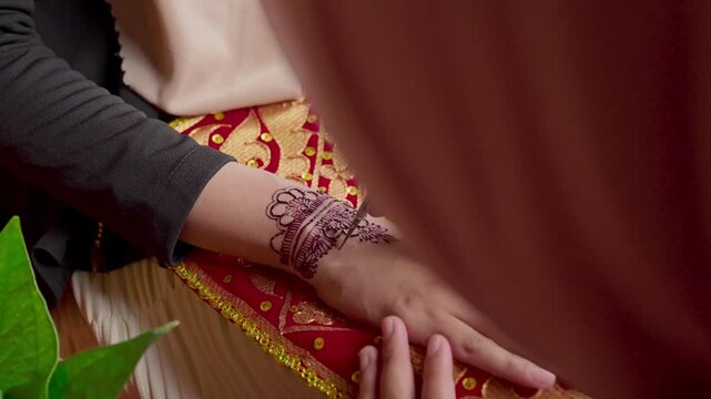 The process of painting henna on the bride's hands. There are many different names for henna tattoo across the globe, such as mehndi, inai, hina, camphire, and hena