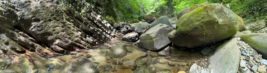 The river runs along the rocky cliffs in the mountains