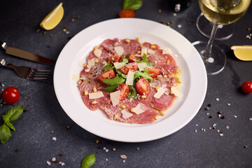 cooking tuna carpaccio - cherry tomato pieces on a plate with raw tuna fillet slices