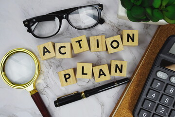 Action Plan with wooden blocks alphabet letters and Magnifying glass and calculator on marble...