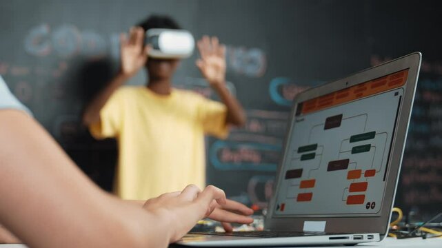 Closeup of school girl hand coding program while african student using VR interact with metaworld. Smart boy wearing virtual reality glasses and playing video games at innovative class. Edification