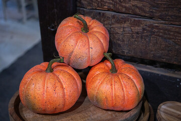 Three orange pumpkins on a rustic wooden barrel in a market