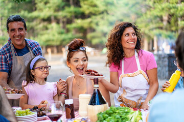 Happy family enjoying outdoor barbecue, multigenerational picnic in nature, summer gathering with...