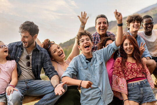 Diverse group celebrating outdoors, joyful friends and family, multicultural gathering with genuine excitement