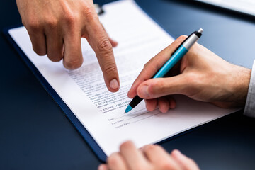 Pointing The Finger In Front Of A Person Signing With Golden Pen On The Document