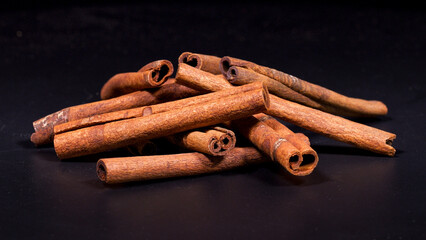 Close-up footage of cinnamon sticks on black background.