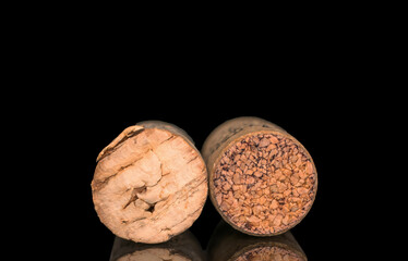Two wine corks, macro, isolated on black background.