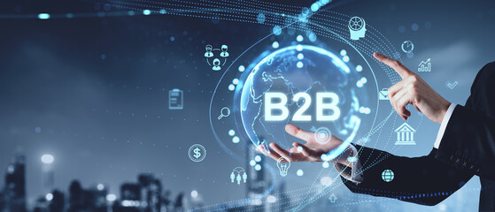 Businessman pointing at a digital B2B concept with various icons and a globe on a dark background. Concept of business, technology, and network