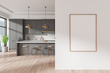Modern kitchen interior with a blank poster frame on the wall. Grey cabinetry, gold accents, and...