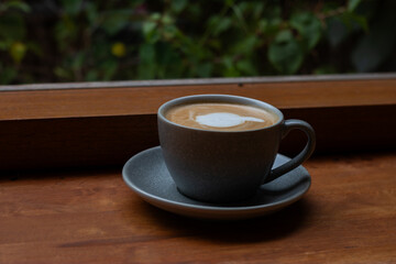 A cup of coffee, hot Latte, lace on the wooden table with a natural background.