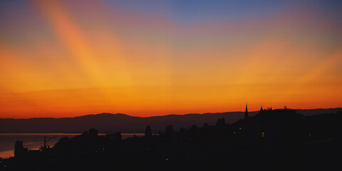 Beautiful sunset with dramatic orange yellow rays of light on dark blue sky