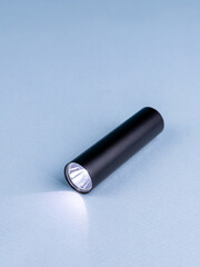 Close up of small and powerful handheld flashlight for travel on blue background