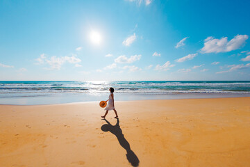 happy girl in a white dress walks along the beach and enjoys her vacation. Carefree girl on the beach on a sunny day.