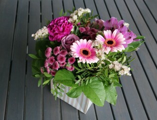 Blumen kreativ arrangiert stehen aif Tisch aus Holz im Garten