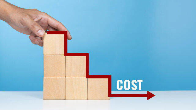 Concept of cost, lean or cost reduction. Hand hold wooden block with the word cost and down arrow for decreasing expense to maximize profits