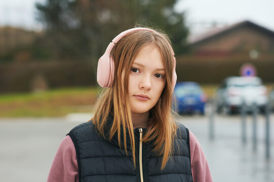 Portrait of 13 - 14 year old teenager girl posing outdoors, wearing headphones