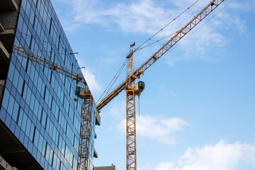 During the day, a crane is seen in front of a building under construction