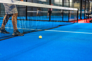 Tennis ball next to the net while friends playing indoors