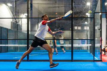 Mature man trying to reach the ball playing paddle tennis