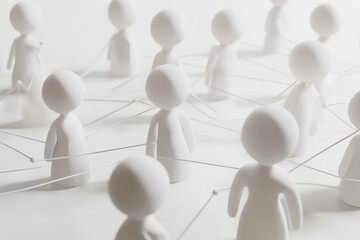 Obraz premium Abstract representation of community connections with white figures linked by threads on a light background