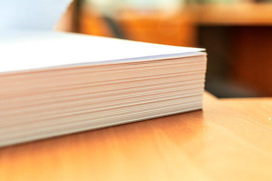 Stacks of white papers work large stacks of papers stacked together. On a desk in an office. Documents that are yet to be printed or made. Business concept.