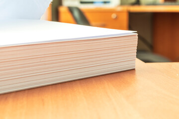 Stacks of white papers work large stacks of papers stacked together. On a desk in an office. Documents that are yet to be printed or made. Business concept.