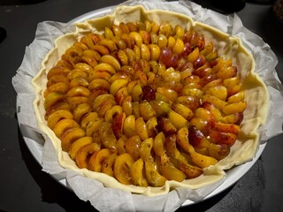 Unbaked Fruit Tart with Sliced Yellow and Red Mirabelle of Lorraine Plums Neatly Arranged on Pastry Dough in a Round Baking Pan, Ready for Baking and Perfect for a Homemade Dessert
